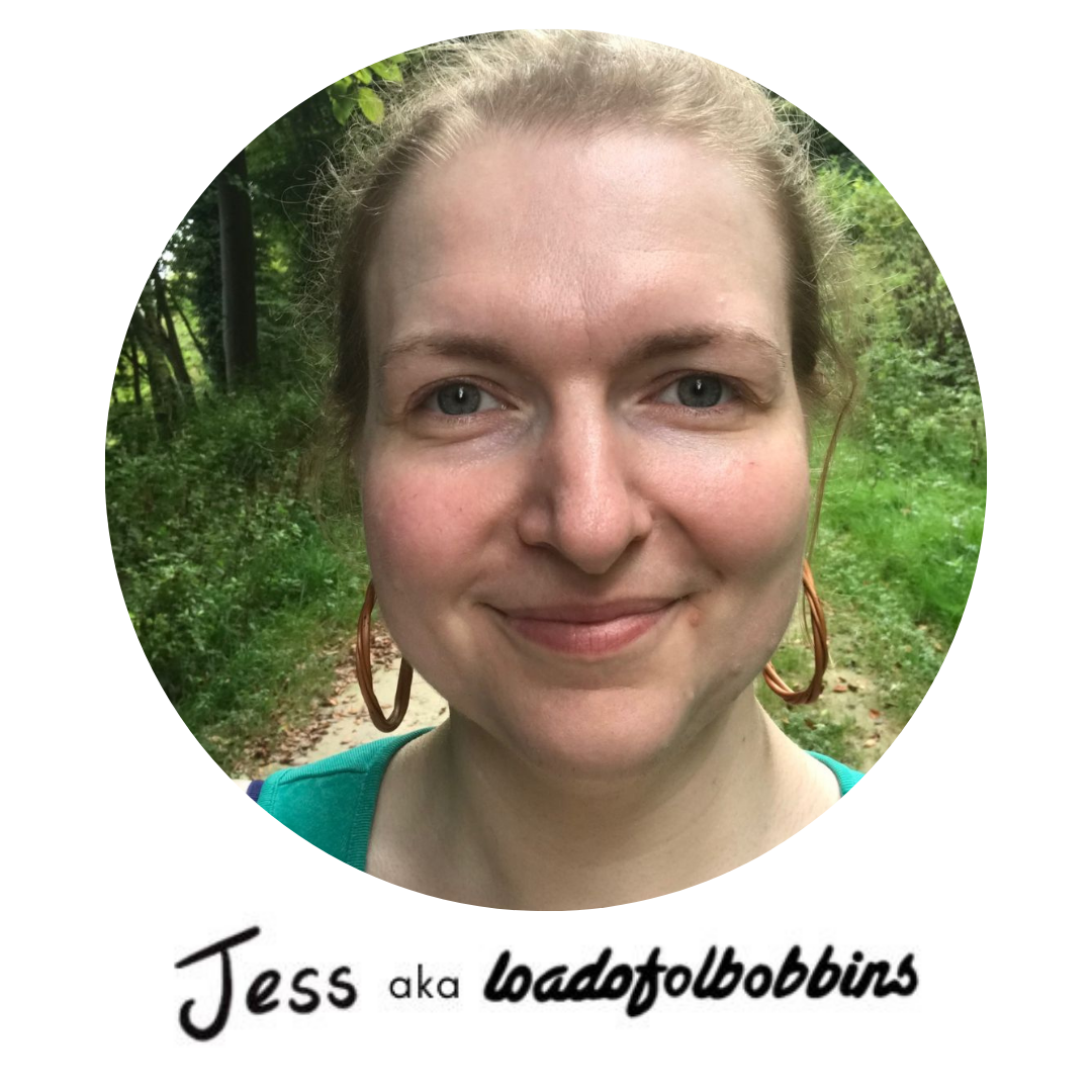 A photograph of Jess aka Loadofolbobbins a smiling and friendly looking white woman with hair up and standing in a forest path. 